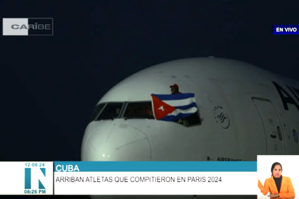 López, único atleta en el mundo en lograr cinco preseas doradas en ediciones consecutivas en una disciplina individual, sacó sus 130 kilogramos de peso por la ventanilla, a la diestra del capitán de la nave, para ondear la enseña nacional.